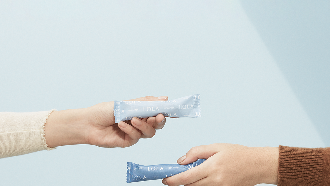 Two hands extended, each holding a Lola tampon