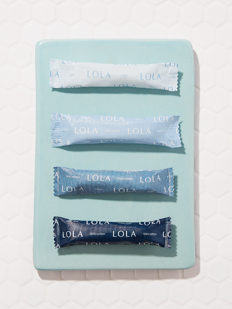 Compact plastic applicator tampons | Front view of four compact tampons on a blue plate
