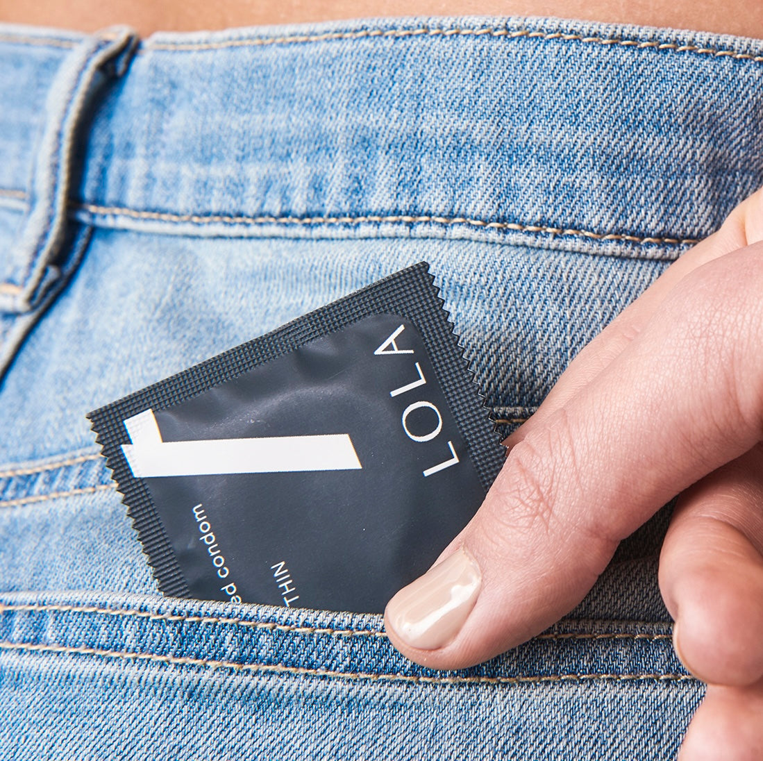 Person putting a Lola condom into their back pocket